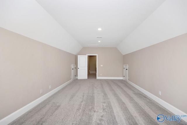 additional living space featuring vaulted ceiling and light carpet