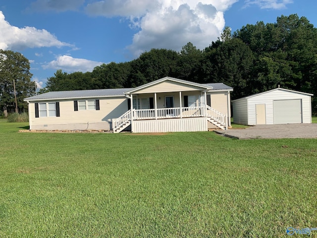 manufactured / mobile home featuring a porch, a garage, a front lawn, and an outbuilding