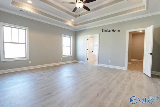 unfurnished bedroom featuring light wood-style floors, a tray ceiling, and ornamental molding