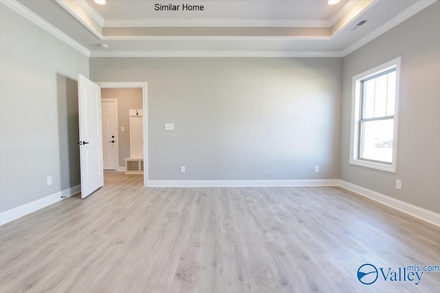 unfurnished room with ornamental molding, a tray ceiling, and light wood finished floors