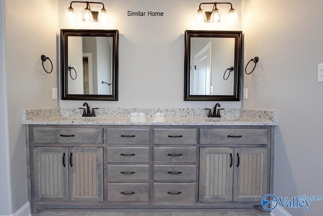 bathroom featuring double vanity, baseboards, and a sink