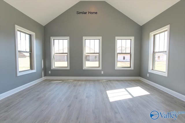 empty room featuring lofted ceiling, light wood-style floors, and baseboards