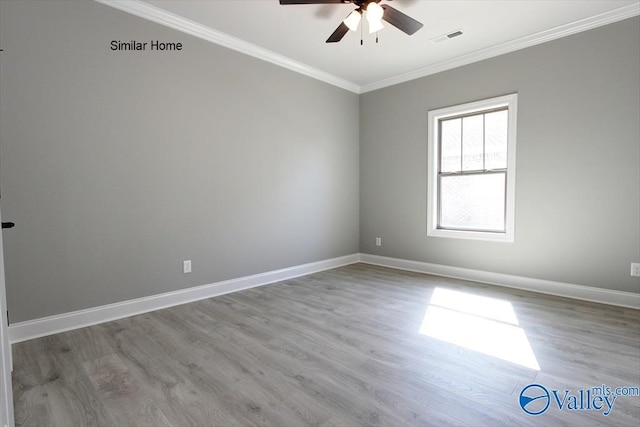 spare room featuring baseboards, visible vents, wood finished floors, and ornamental molding