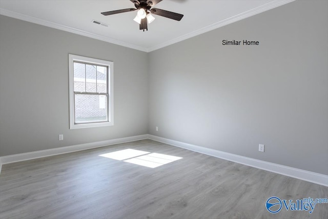 spare room featuring baseboards, visible vents, crown molding, and light wood finished floors