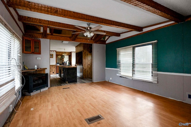 unfurnished living room with hardwood / wood-style flooring, ceiling fan, beam ceiling, and sink