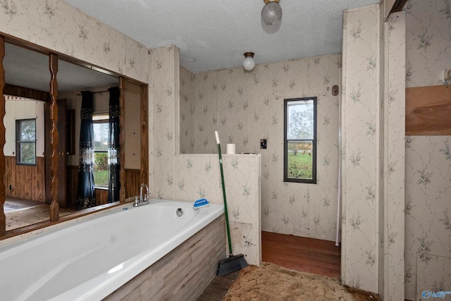 bathroom featuring hardwood / wood-style floors, a textured ceiling, and a tub