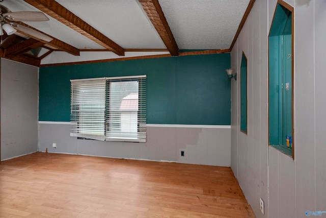 empty room featuring wood-type flooring, vaulted ceiling with beams, a textured ceiling, wood walls, and ceiling fan