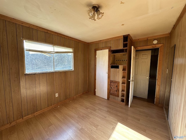 unfurnished bedroom with light hardwood / wood-style floors and wood walls