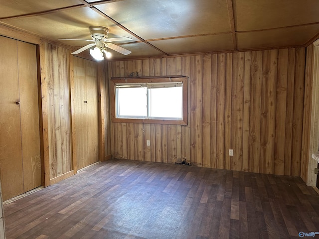 unfurnished room with ceiling fan, dark wood-type flooring, and wooden walls