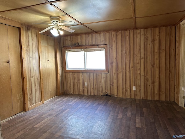 unfurnished room with wood walls, ceiling fan, and dark hardwood / wood-style floors