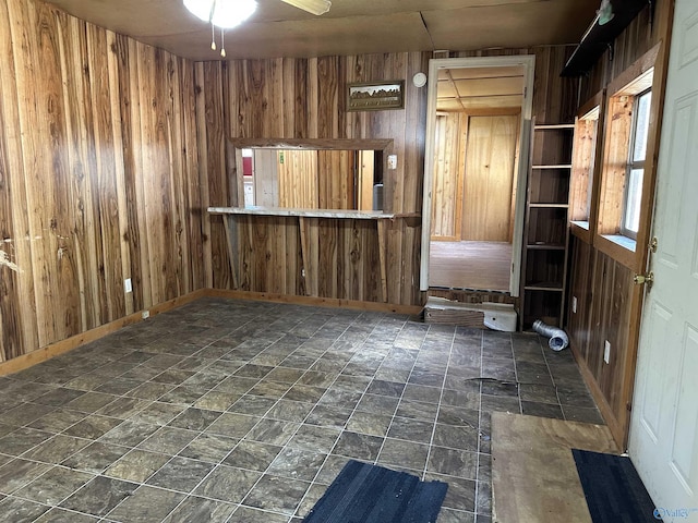 interior space with ceiling fan and wooden walls