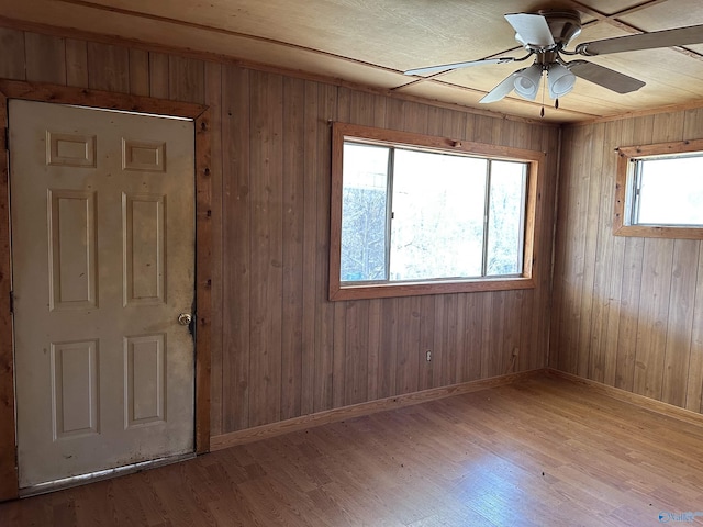 spare room featuring wooden walls, ceiling fan, and light hardwood / wood-style floors