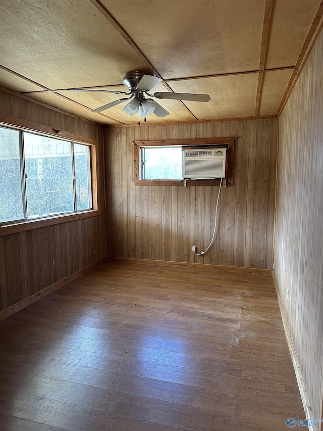 unfurnished room with hardwood / wood-style floors, ceiling fan, wood walls, and a wall unit AC