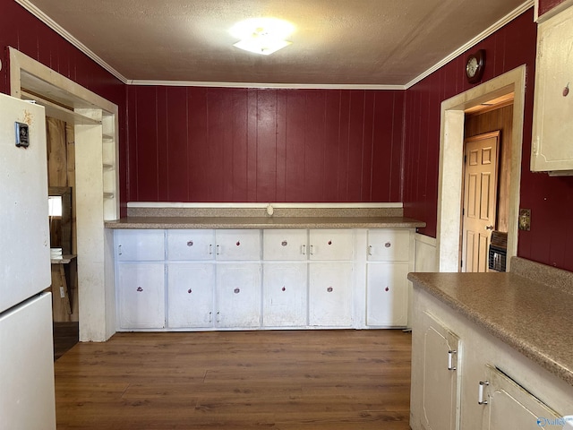 kitchen featuring dark hardwood / wood-style flooring, a textured ceiling, crown molding, white fridge, and wood walls