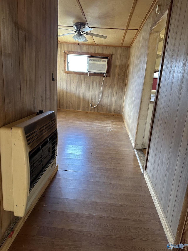 interior space with an AC wall unit, heating unit, wooden walls, and light hardwood / wood-style flooring