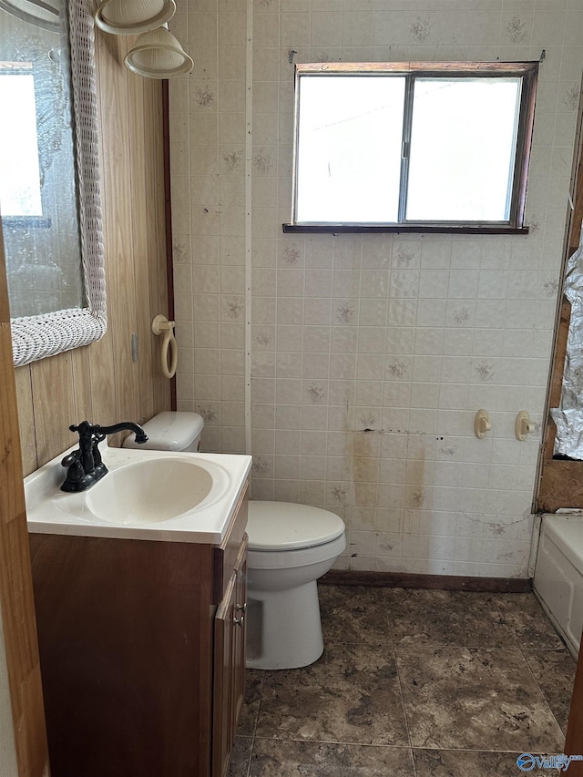 bathroom with vanity, a bathtub, toilet, and a wealth of natural light