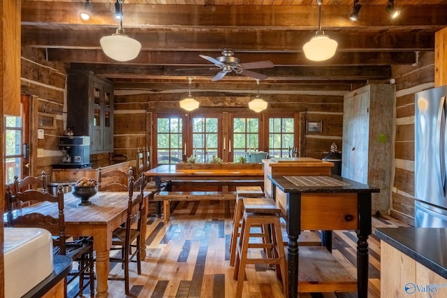 interior space with stainless steel fridge, beam ceiling, ceiling fan, and hardwood / wood-style flooring