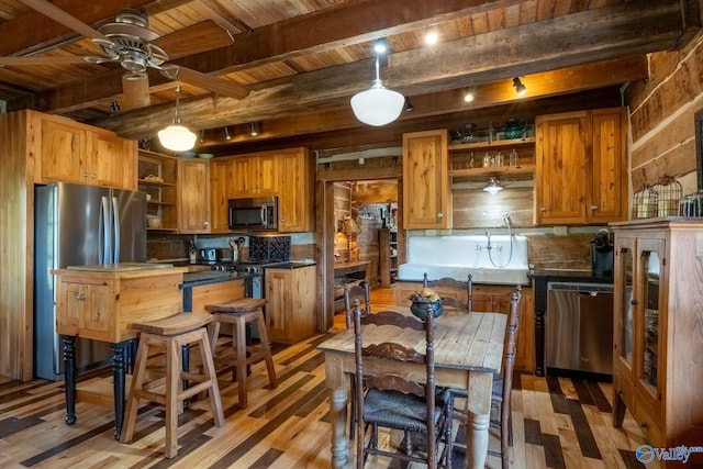 kitchen featuring ceiling fan, hardwood / wood-style flooring, appliances with stainless steel finishes, and beam ceiling