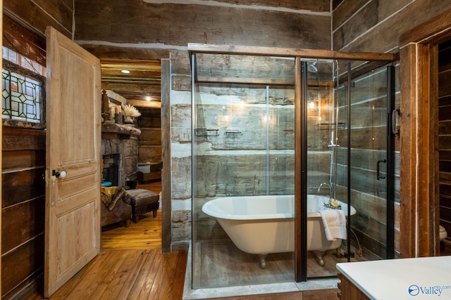 bathroom with wood-type flooring, separate shower and tub, vanity, and a fireplace