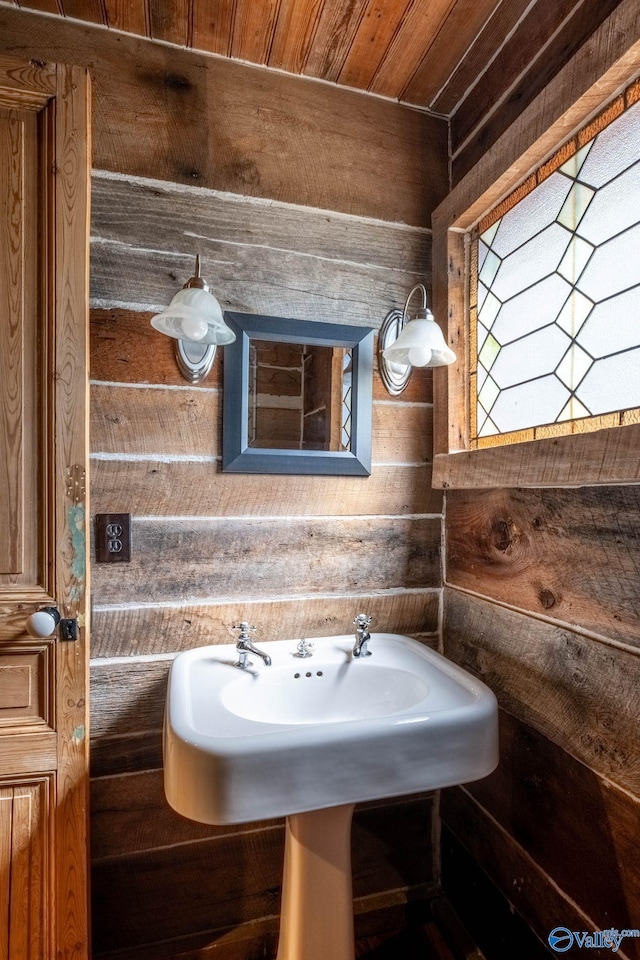 bathroom featuring wooden ceiling, wooden walls, and sink