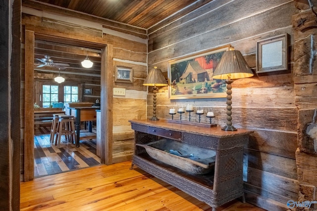 interior space with wood-type flooring, wood ceiling, wood walls, and ceiling fan