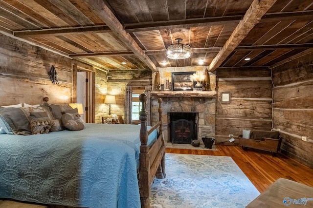 unfurnished bedroom featuring wood-type flooring, beam ceiling, wooden walls, a stone fireplace, and wooden ceiling