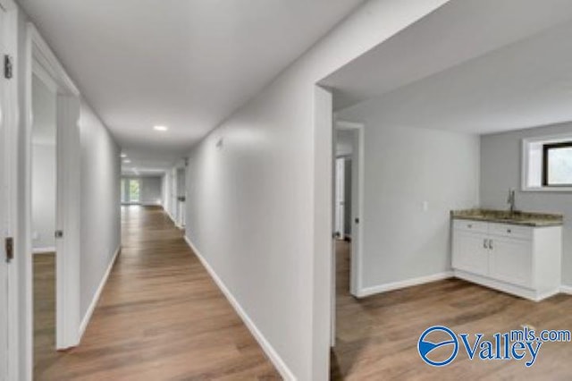 corridor with baseboards and wood finished floors