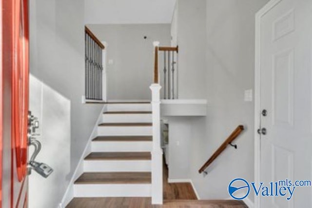 staircase with baseboards and wood finished floors