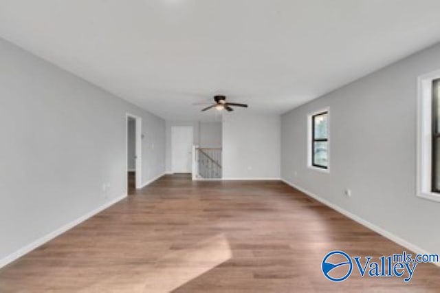 unfurnished living room with ceiling fan, baseboards, and wood finished floors