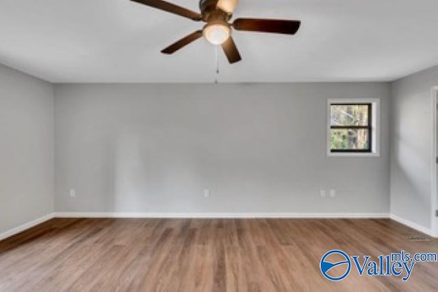 empty room featuring baseboards, wood finished floors, and a ceiling fan