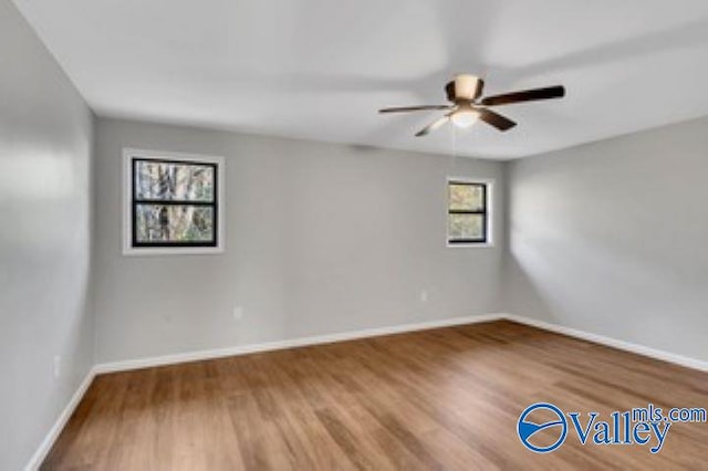 empty room with ceiling fan, baseboards, and wood finished floors