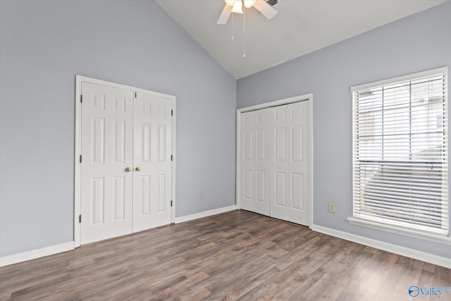 unfurnished bedroom with ceiling fan, high vaulted ceiling, two closets, and hardwood / wood-style flooring