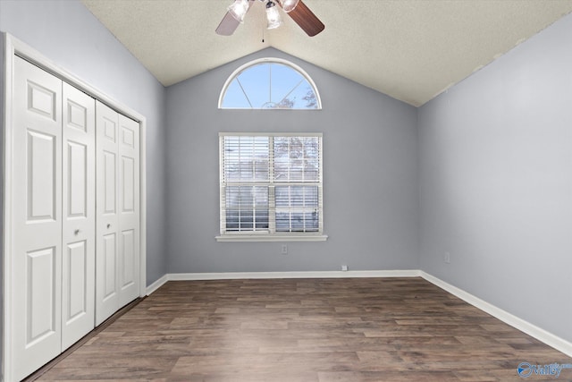 unfurnished bedroom featuring ceiling fan, dark wood-type flooring, a textured ceiling, vaulted ceiling, and a closet