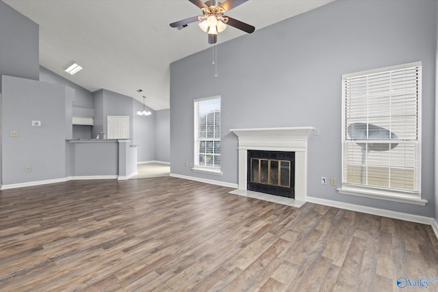 unfurnished living room with hardwood / wood-style floors, ceiling fan with notable chandelier, and high vaulted ceiling