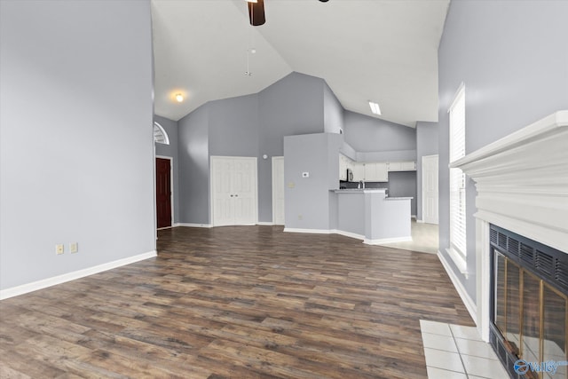 unfurnished living room with hardwood / wood-style floors, ceiling fan, and high vaulted ceiling