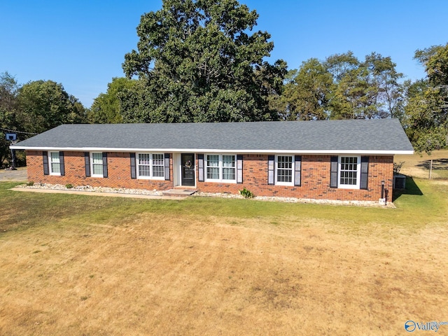 ranch-style home with roof with shingles, a front yard, and brick siding