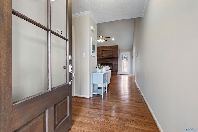 entryway featuring hardwood / wood-style floors, a fireplace, ornamental molding, ceiling fan, and a textured ceiling