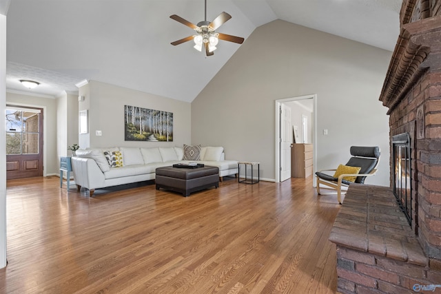 living room featuring crown molding, ceiling fan, hardwood / wood-style floors, high vaulted ceiling, and a fireplace