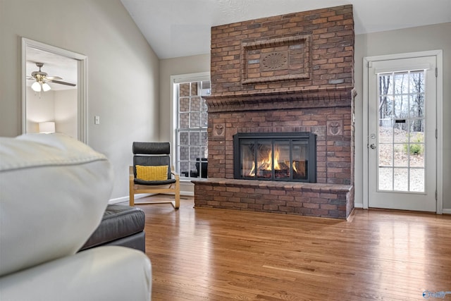 living room with lofted ceiling, a brick fireplace, and wood-type flooring