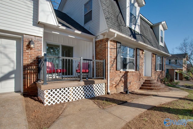 exterior space with a garage, brick siding, and roof with shingles