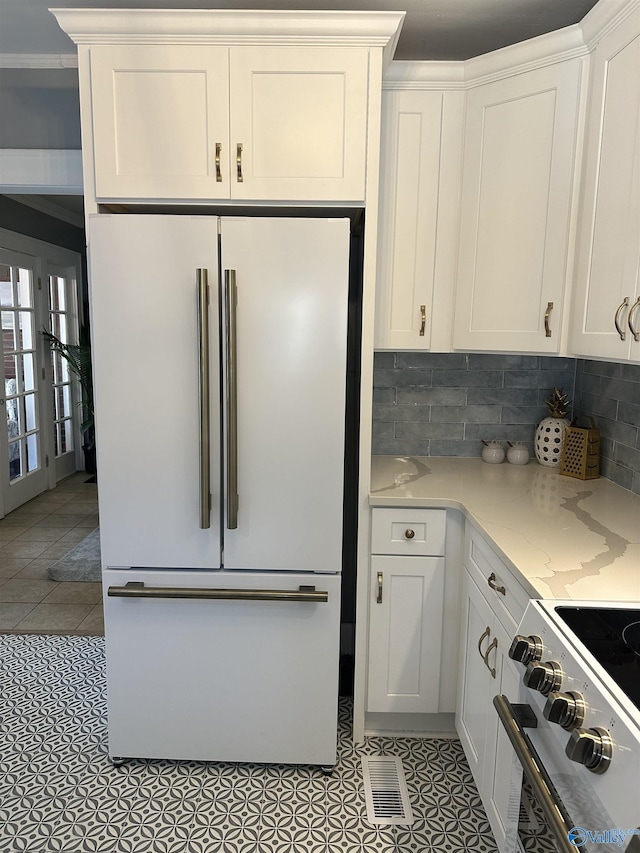 kitchen with visible vents, white cabinets, light stone counters, refrigerator, and stainless steel electric stove