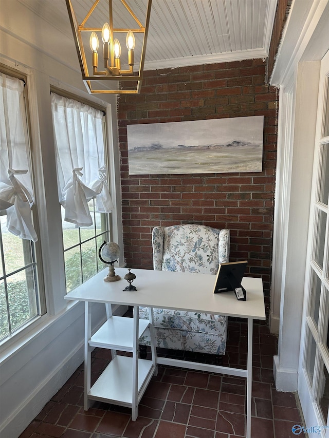 interior space with an inviting chandelier, brick wall, ornamental molding, and baseboards