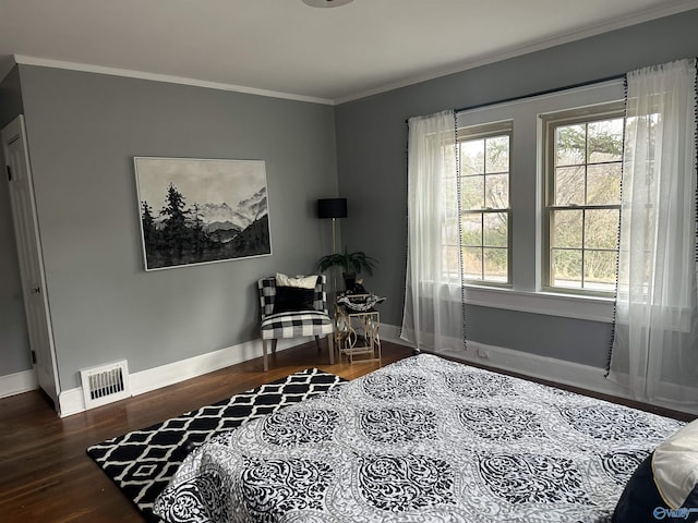 bedroom featuring ornamental molding, visible vents, baseboards, and wood finished floors