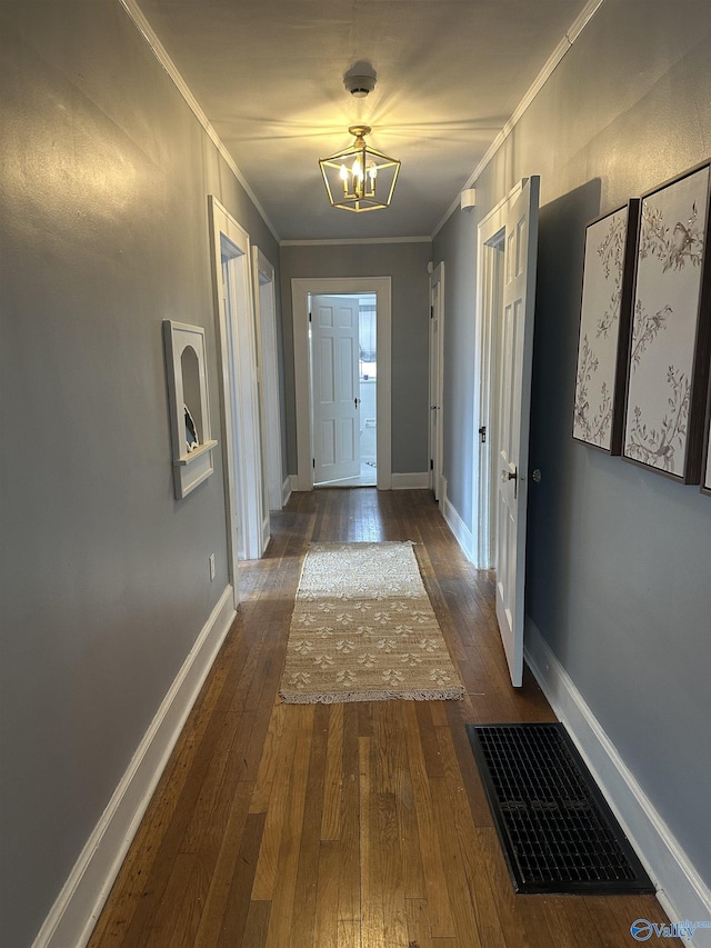 doorway to outside with dark wood-style floors, a notable chandelier, baseboards, and crown molding