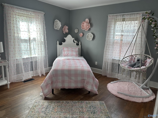 bedroom with ornamental molding, visible vents, baseboards, and wood finished floors