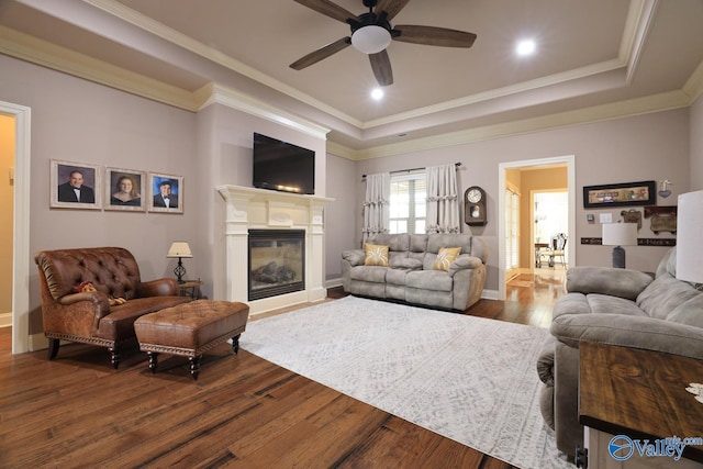 living room featuring wood-type flooring, ceiling fan, crown molding, and a tray ceiling