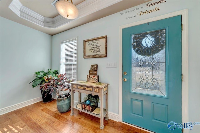 foyer entrance featuring hardwood / wood-style flooring, ornamental molding, and a raised ceiling