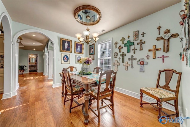 dining space with a notable chandelier and light hardwood / wood-style flooring