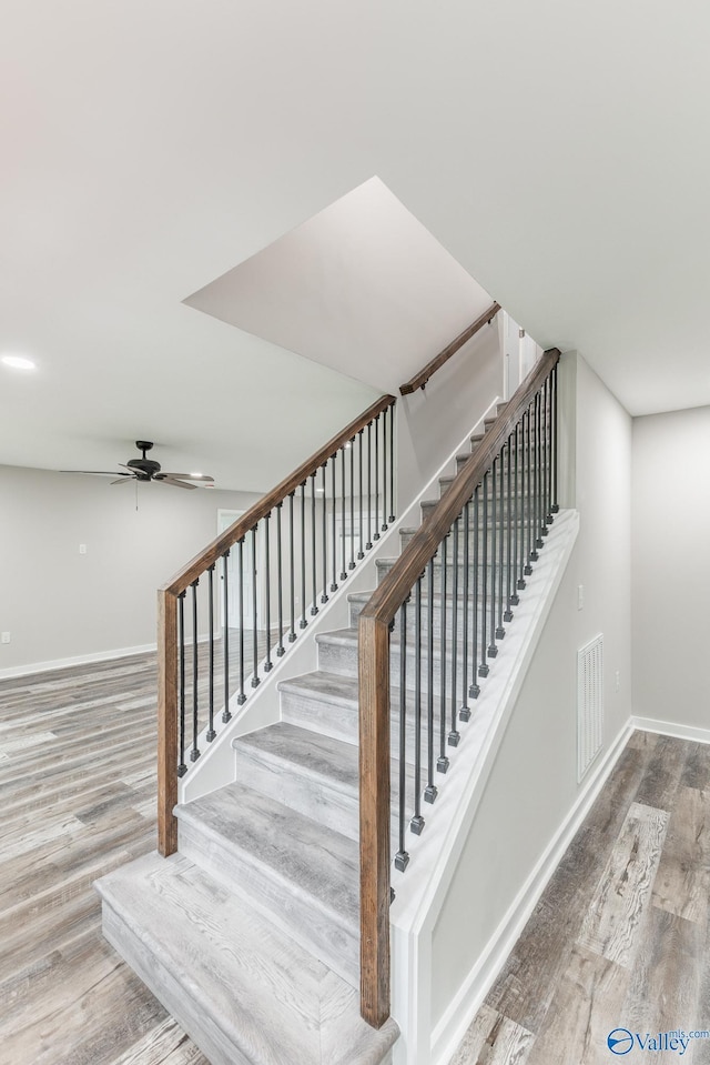 stairs featuring baseboards, ceiling fan, wood finished floors, and visible vents