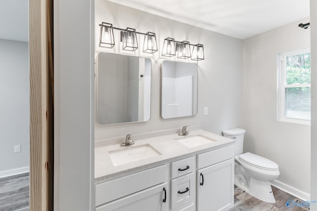 bathroom with double vanity, toilet, a sink, and wood finished floors